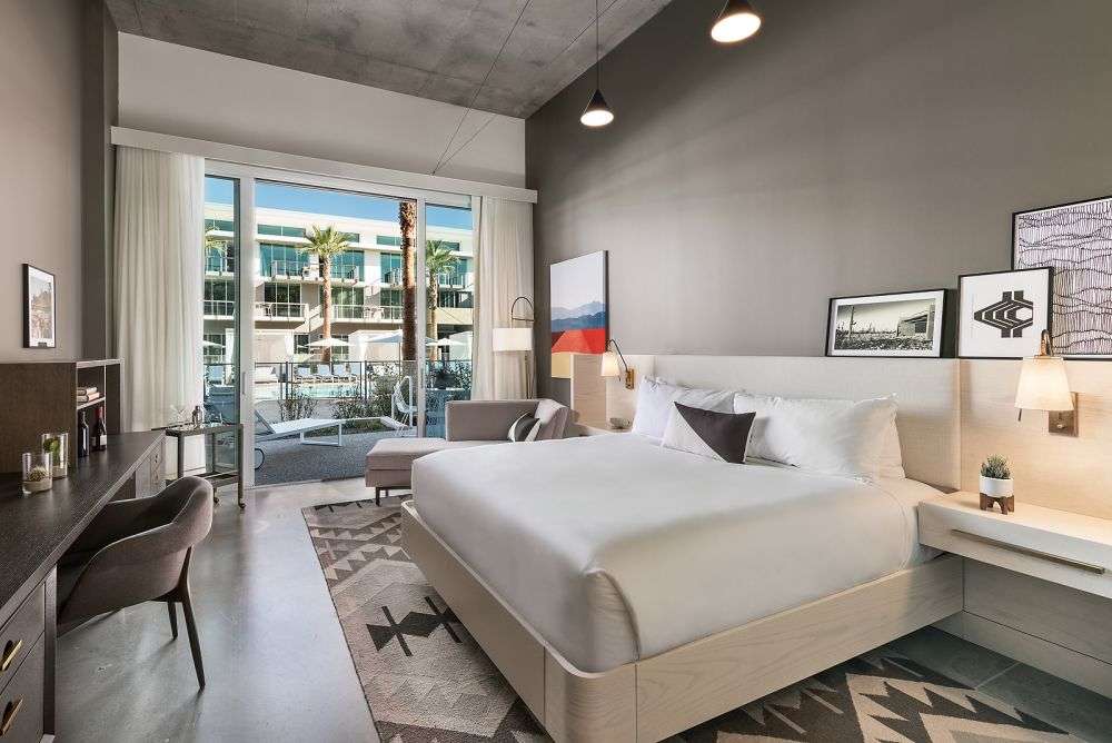 a room with a large bed and glass door that leads to the balcony