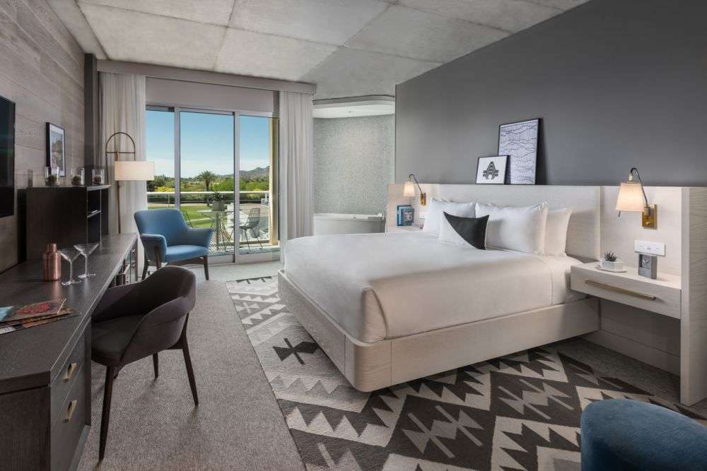 a room featuring a bed with a desk and door to the balcony