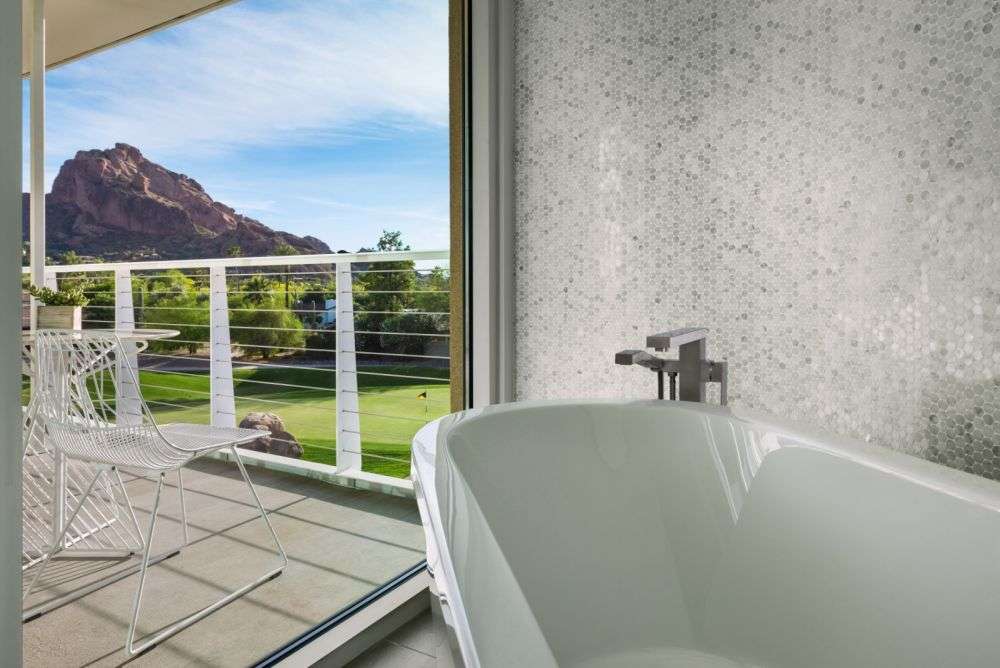 a large bathtub next to chairs on the balcony