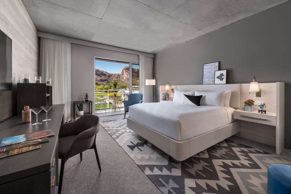a room featuring a bed and desk with a sliding glass door to the outside