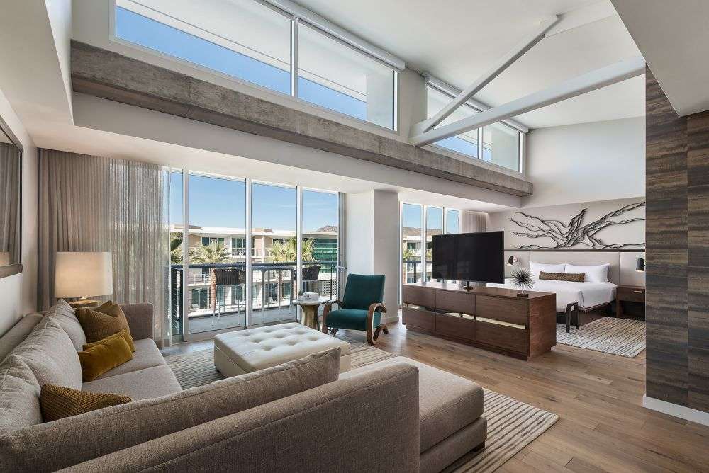 a room featuring couches, a TV and multiple large windows