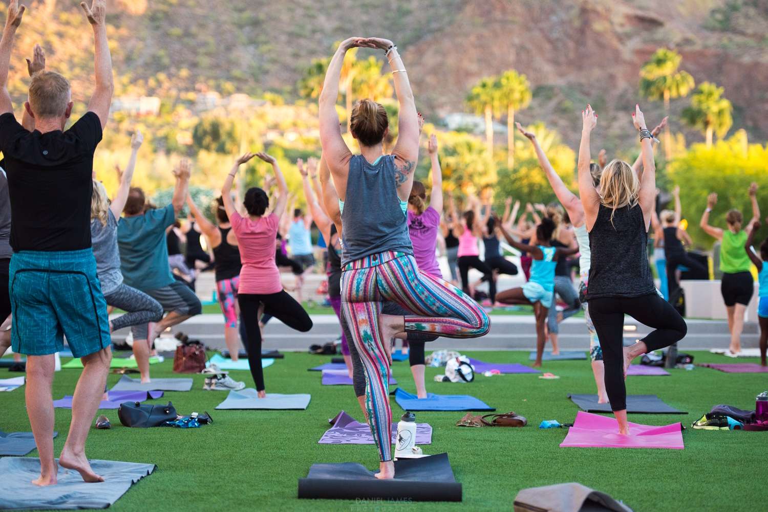 A group of people doing yoga outside facing the mountains.