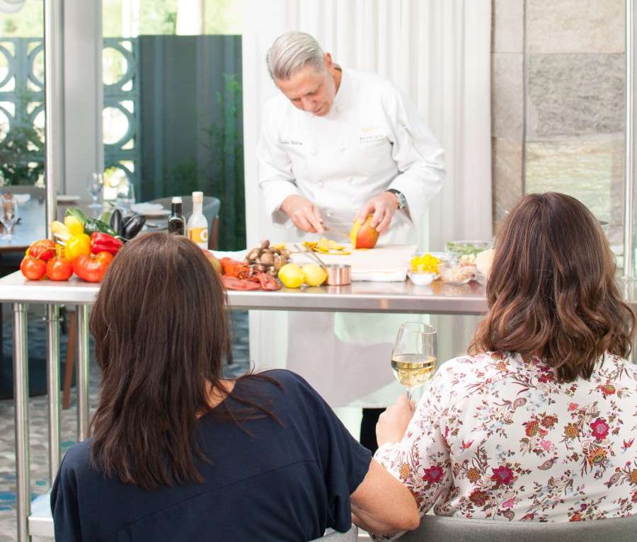 Chef Charles Wiley preparing ingredients in front of two women.