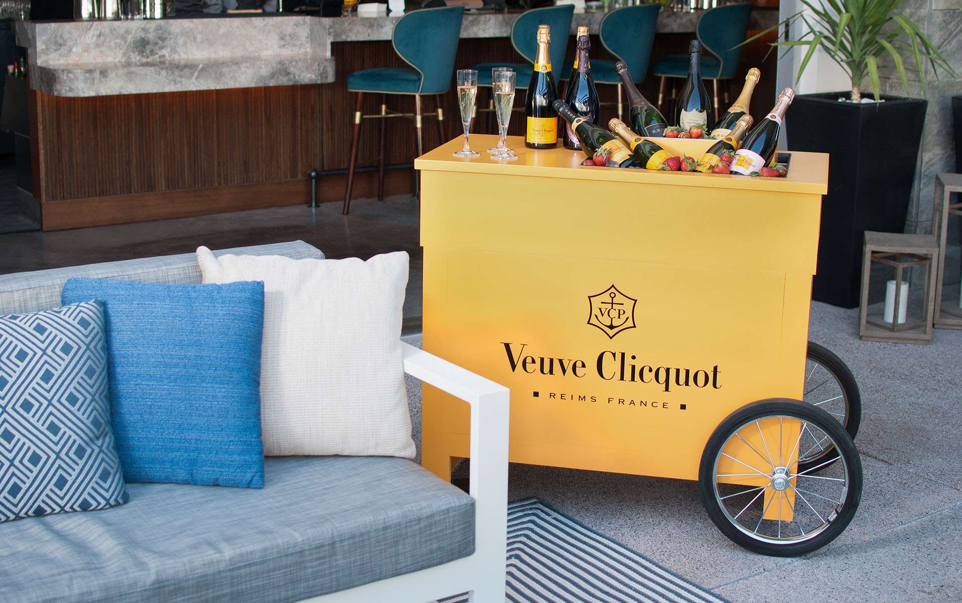 A cart of champagne and strawberries beside a couch.