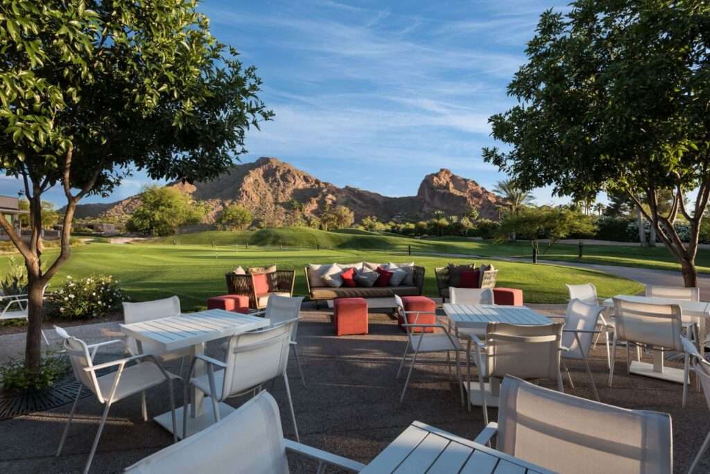 Numerous tables and chairs outside with mountains in the back.