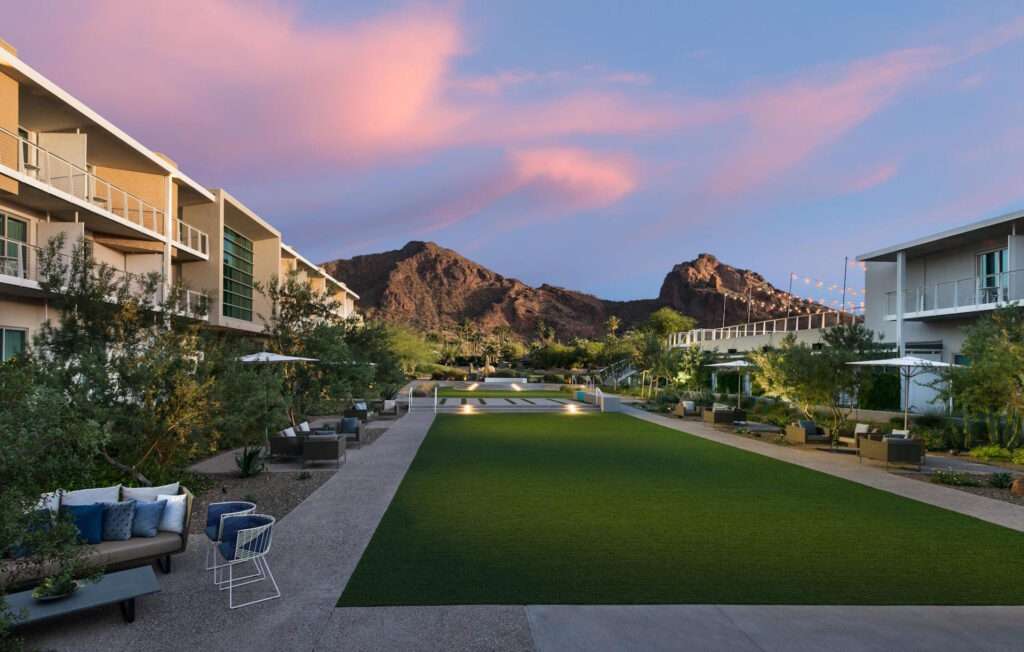 The lawn outside of the resort with mountains and buildings surrounding it.