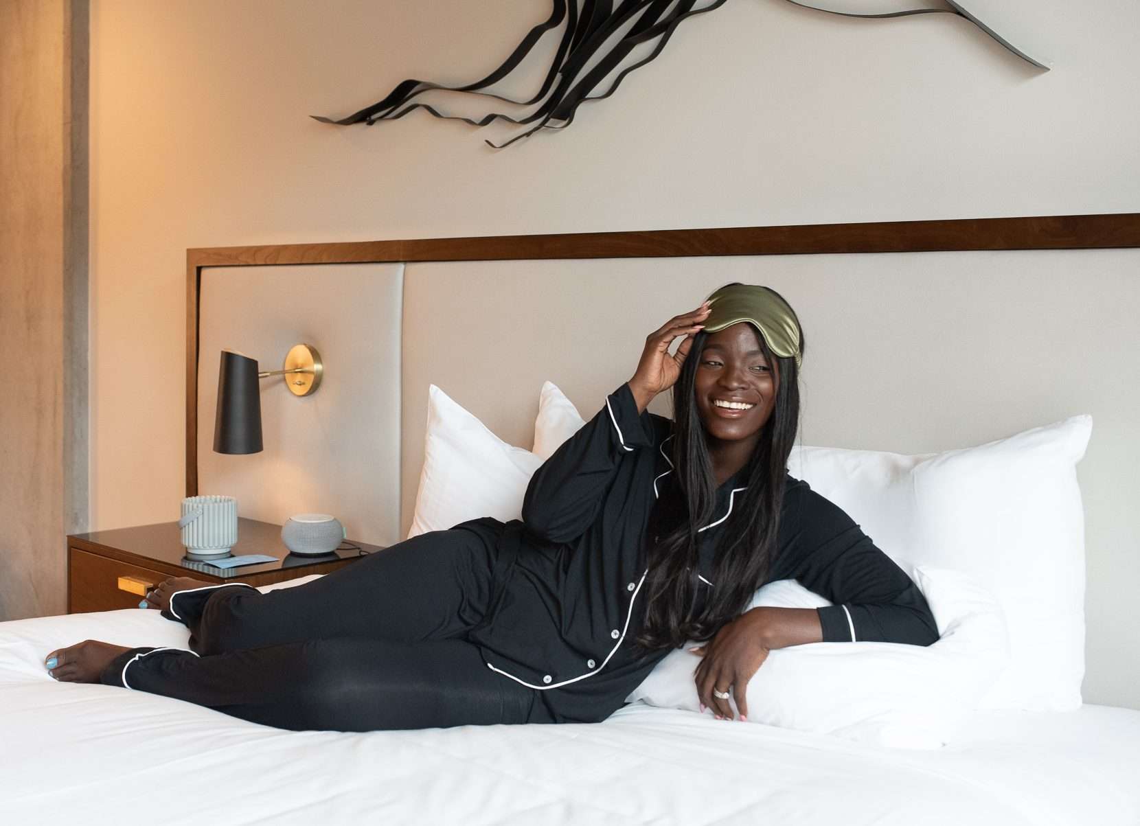 Woman laying on bed wearing pajamas and an eye mask