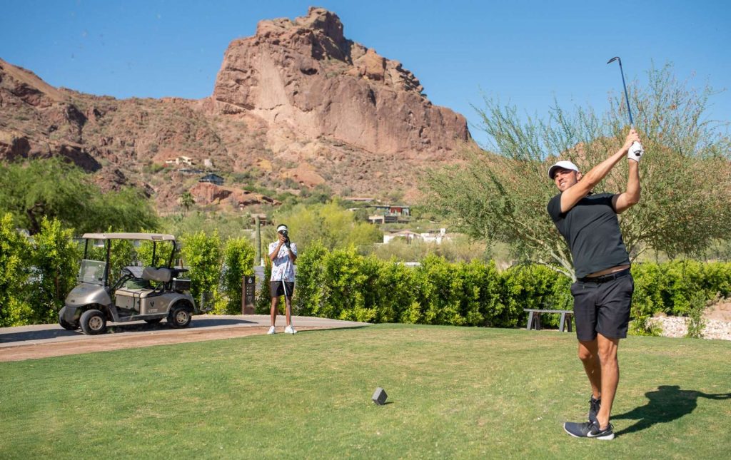 Man golfing with mountain in background
