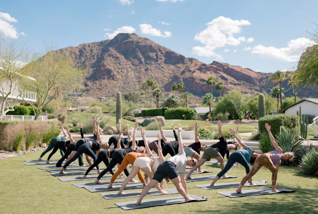 people doing yoga on the lawn with a mountain view