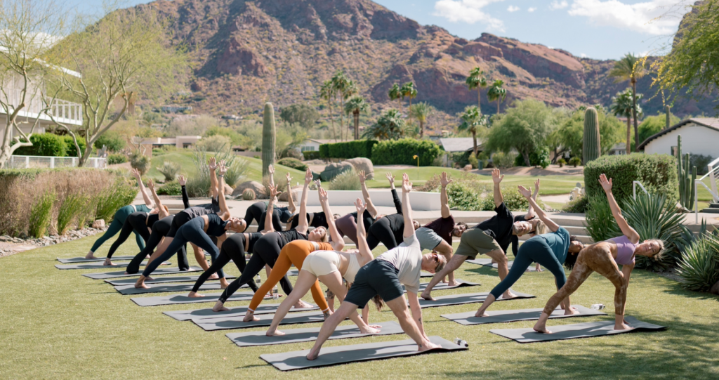 people doing yoga on the lawn with a mountain view